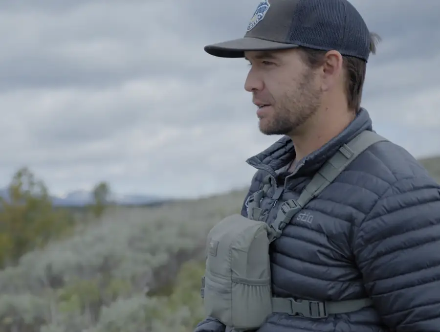 Wildlife guide in a ball cap looking across the sagebrush