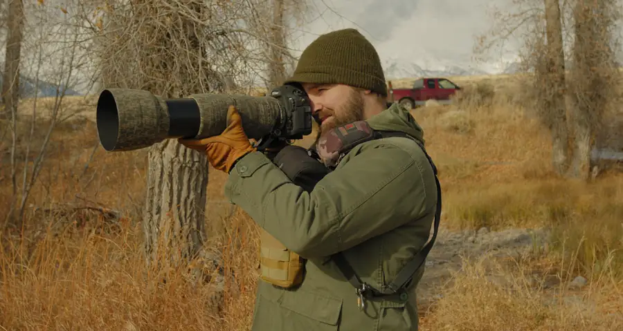 Wildlife photographer with a long telephoto lens in autumn brush
