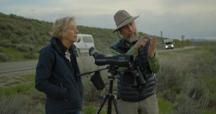 Two guides with a spotting scope beside the road
